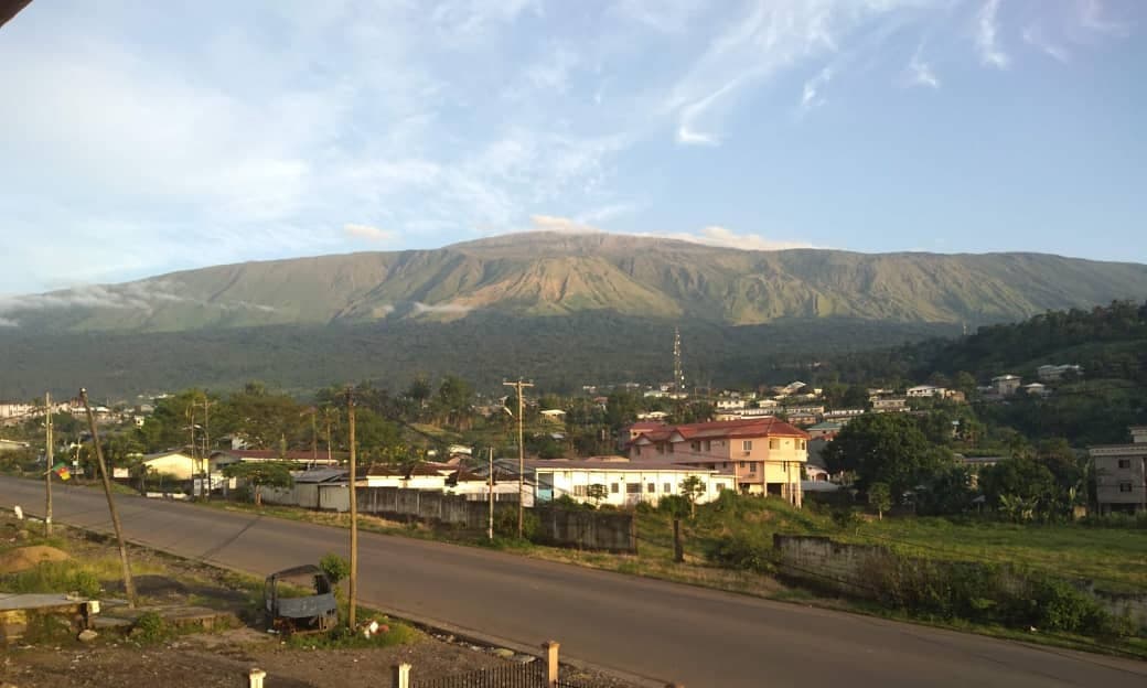 Mount Cameroon rising above green forest with cloud around its peak