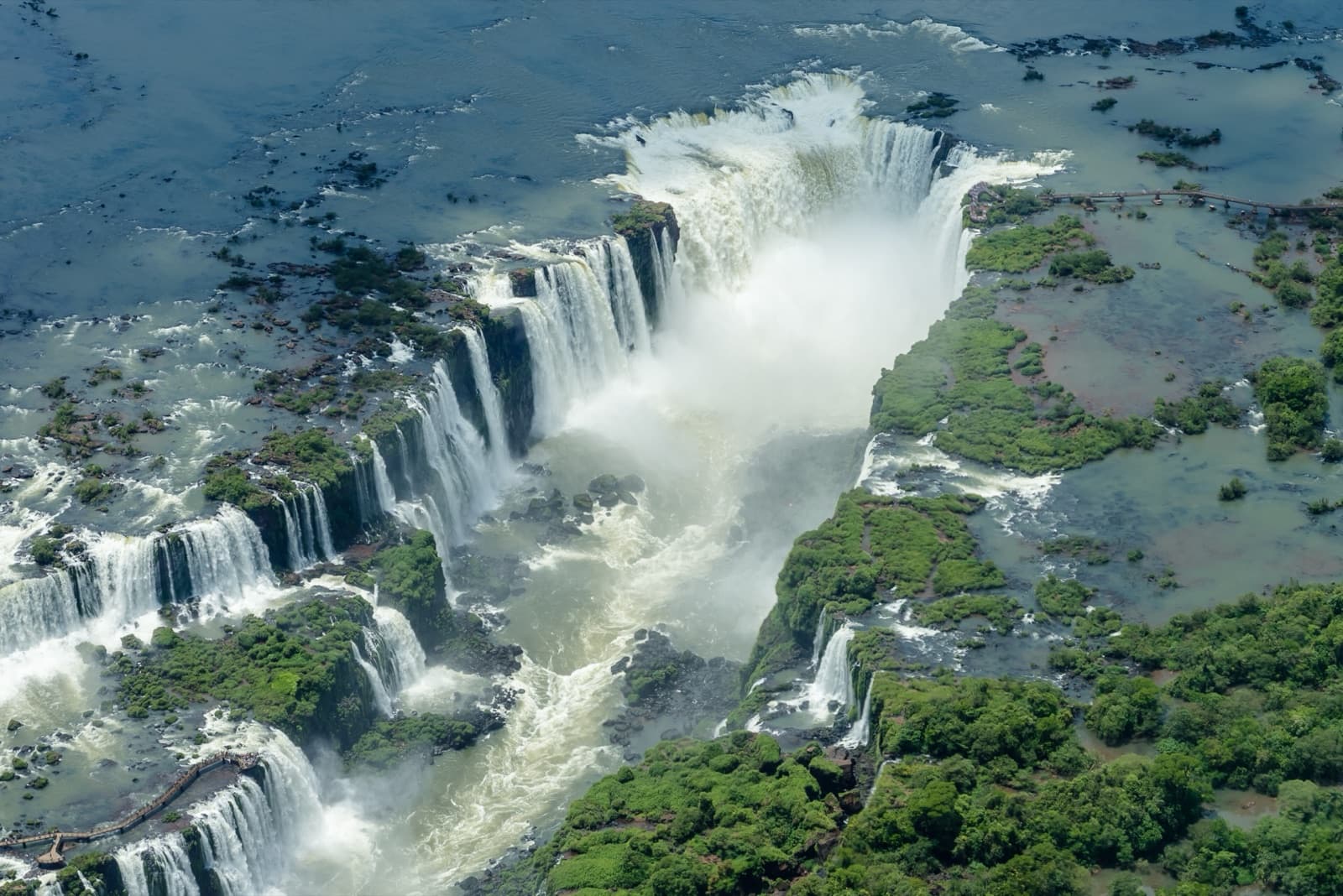 An aerial view of the Iguazú Falls with mist rising over the jungle