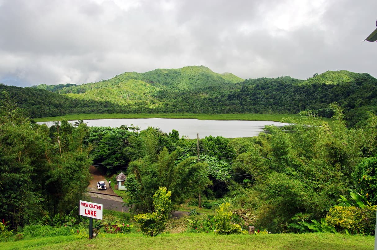 Grand Etang crater lake surrounded by lush rainforest with mist hanging over the water