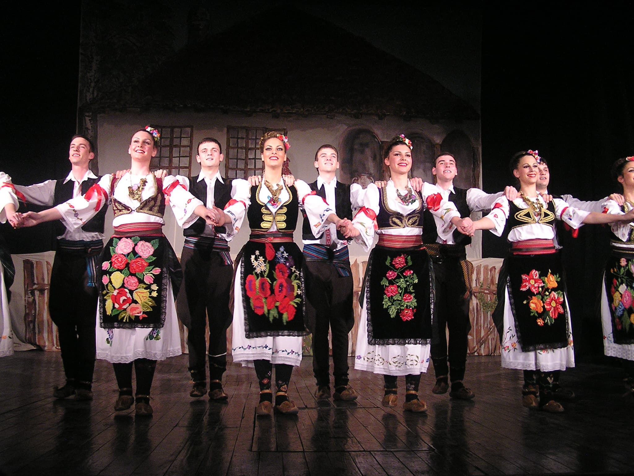 A group of dancers in colourful traditional costumes holding hands in a circle dance