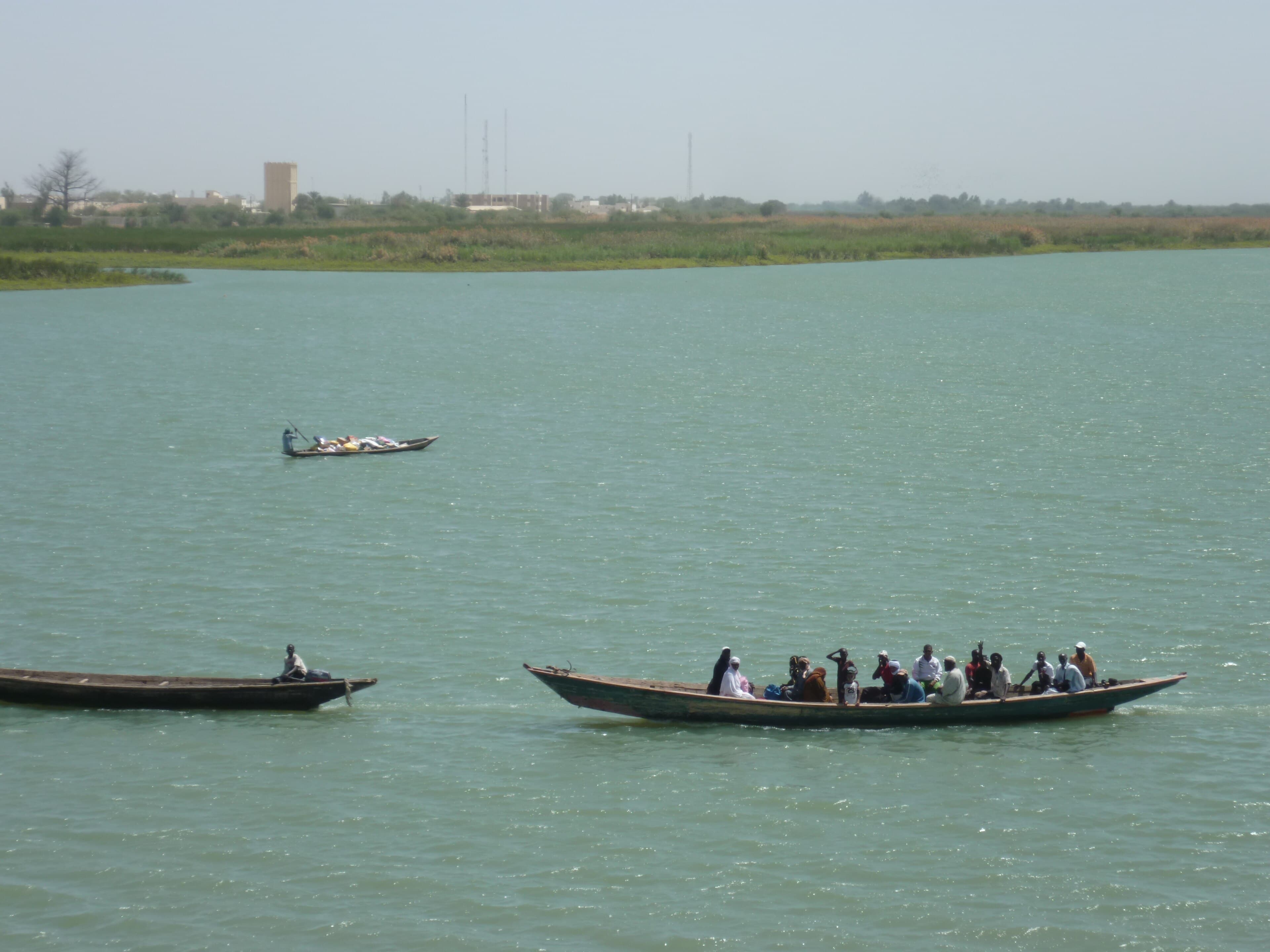 A wide stretch of the Senegal River with boats and green banks