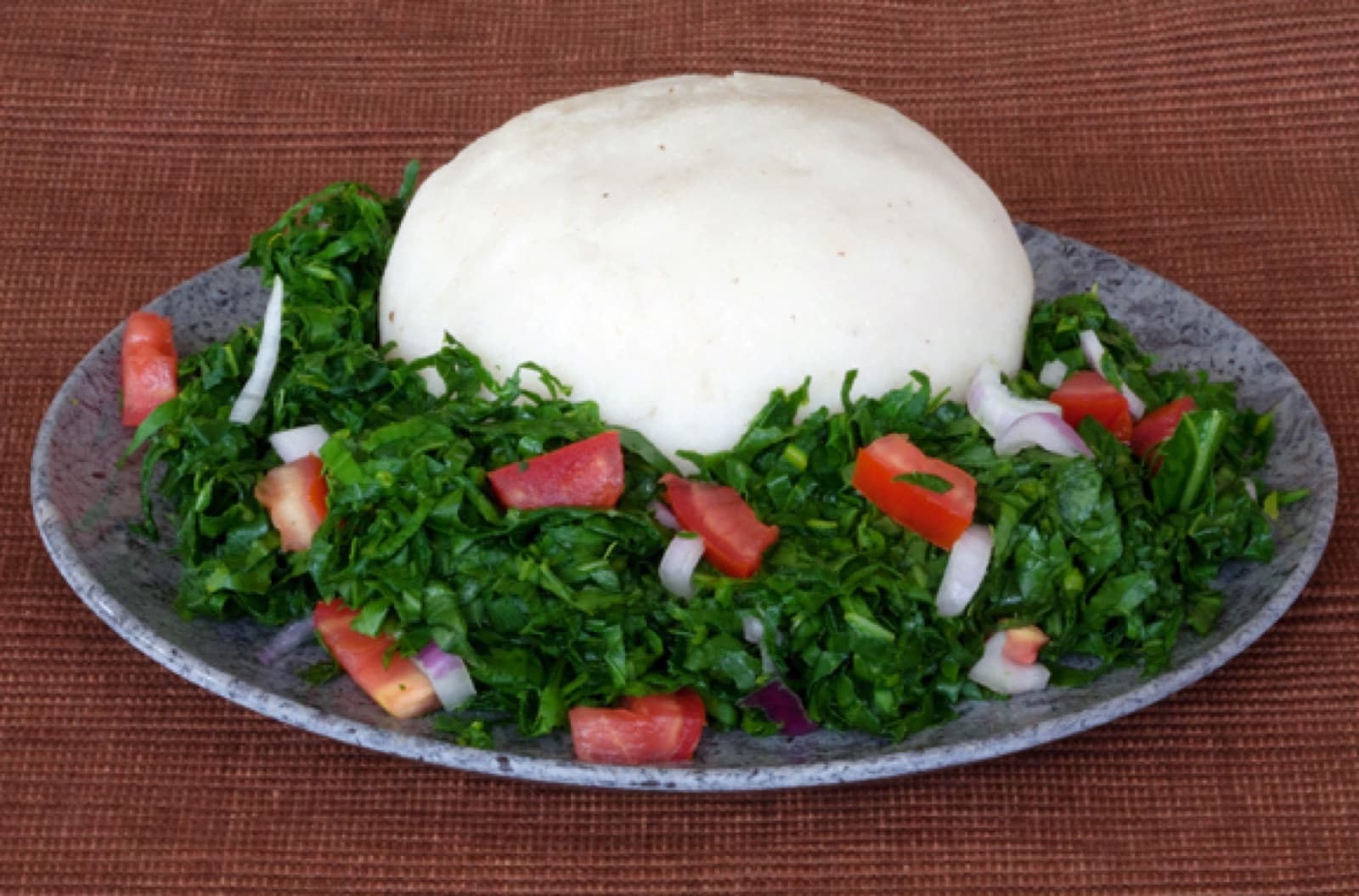 A plate of ugali served alongside vegetable stew